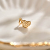 A miniature yellow gold citrus wedge jewellery charm.